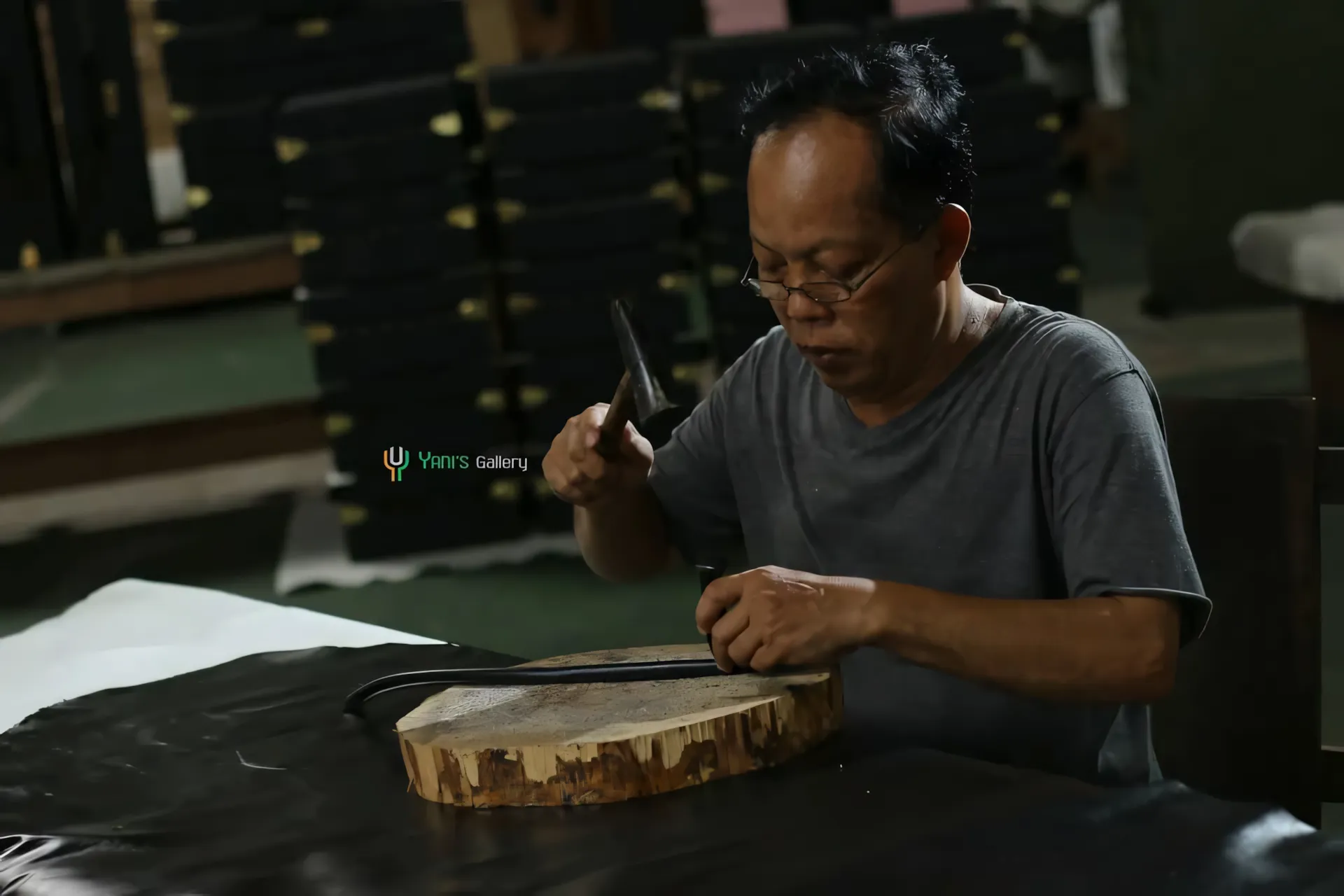 An artisan hand-carving a teak slab at the Yani's Gallery workshop.