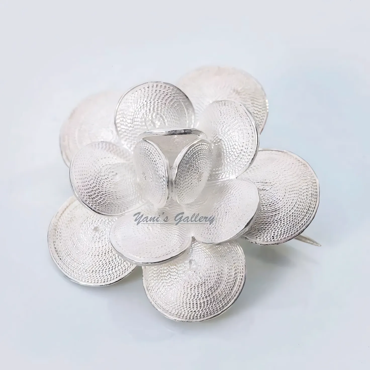 A silver flower brooch with fine textured petals.