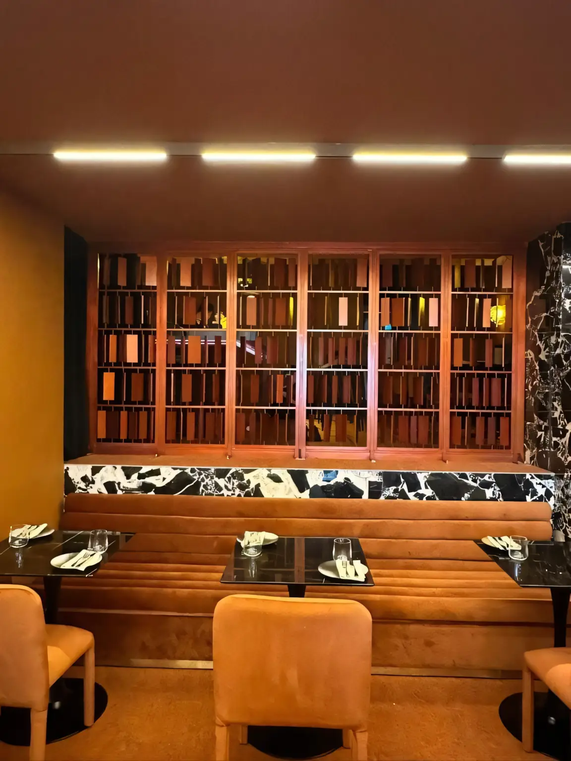 Bar with a lit bookshelf wall and marble counter at 85 Amoy.
